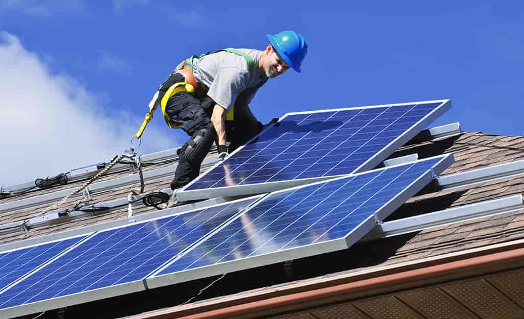 Man installing solar panels on roof.